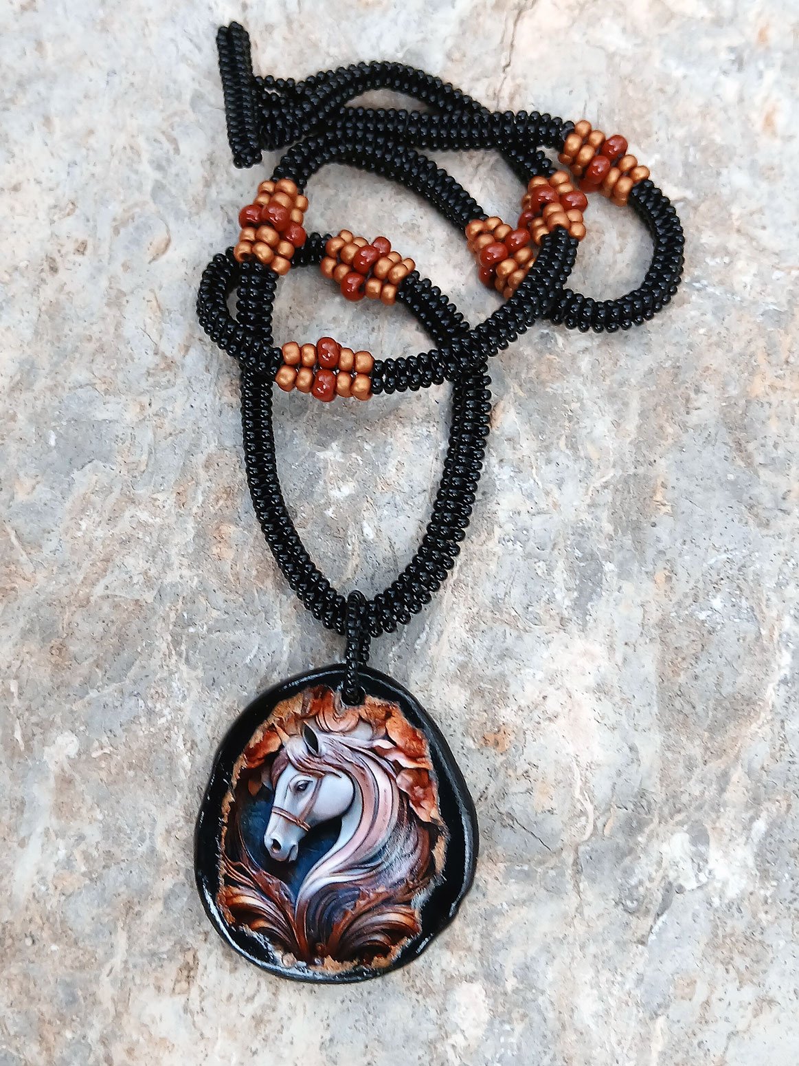 Handmade non-metal beaded rope necklace with horsehead medallion pendant handwoven in black, sienna brown and rust accents and toggle clasp.