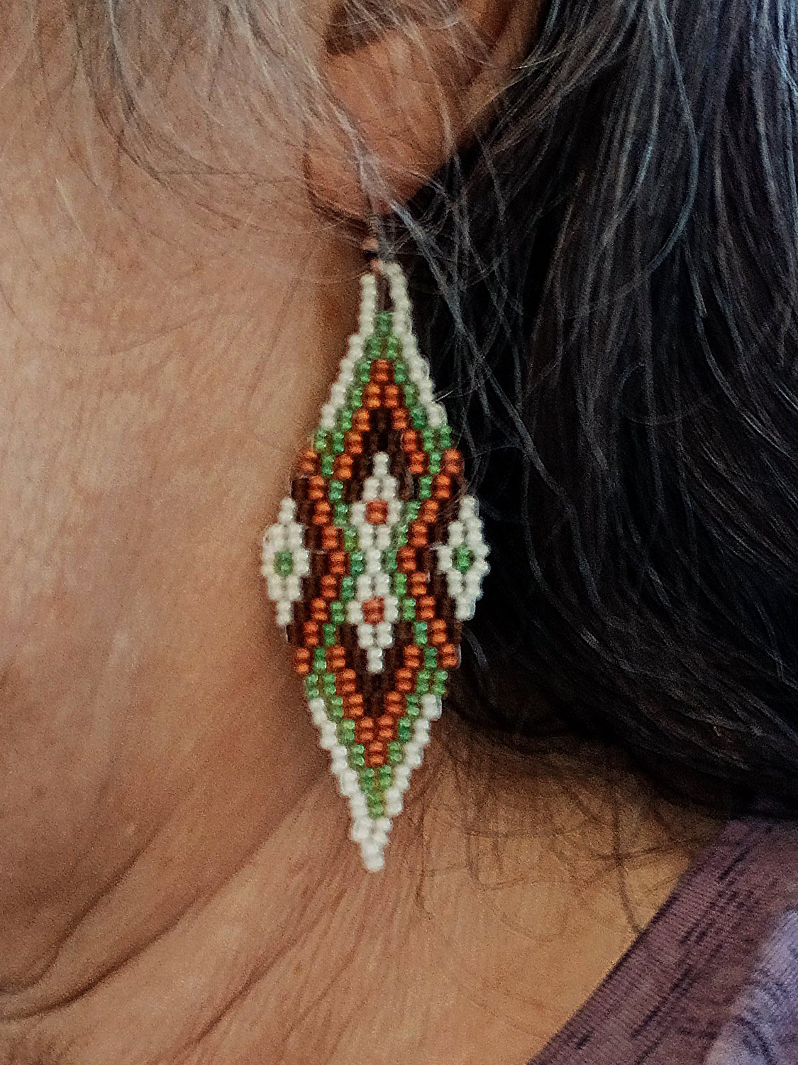 Copper Meridian drop beaded earrings featuring an oblong geometric design on model