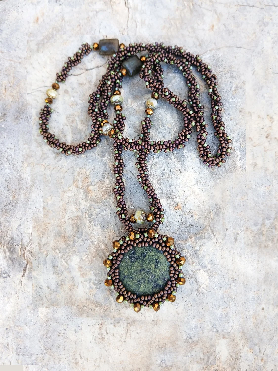 Handmade statement pendant necklace featuring a natural forest green agate gemstone wrapped in handwoven beaded bezel with a brown and bronze chain.