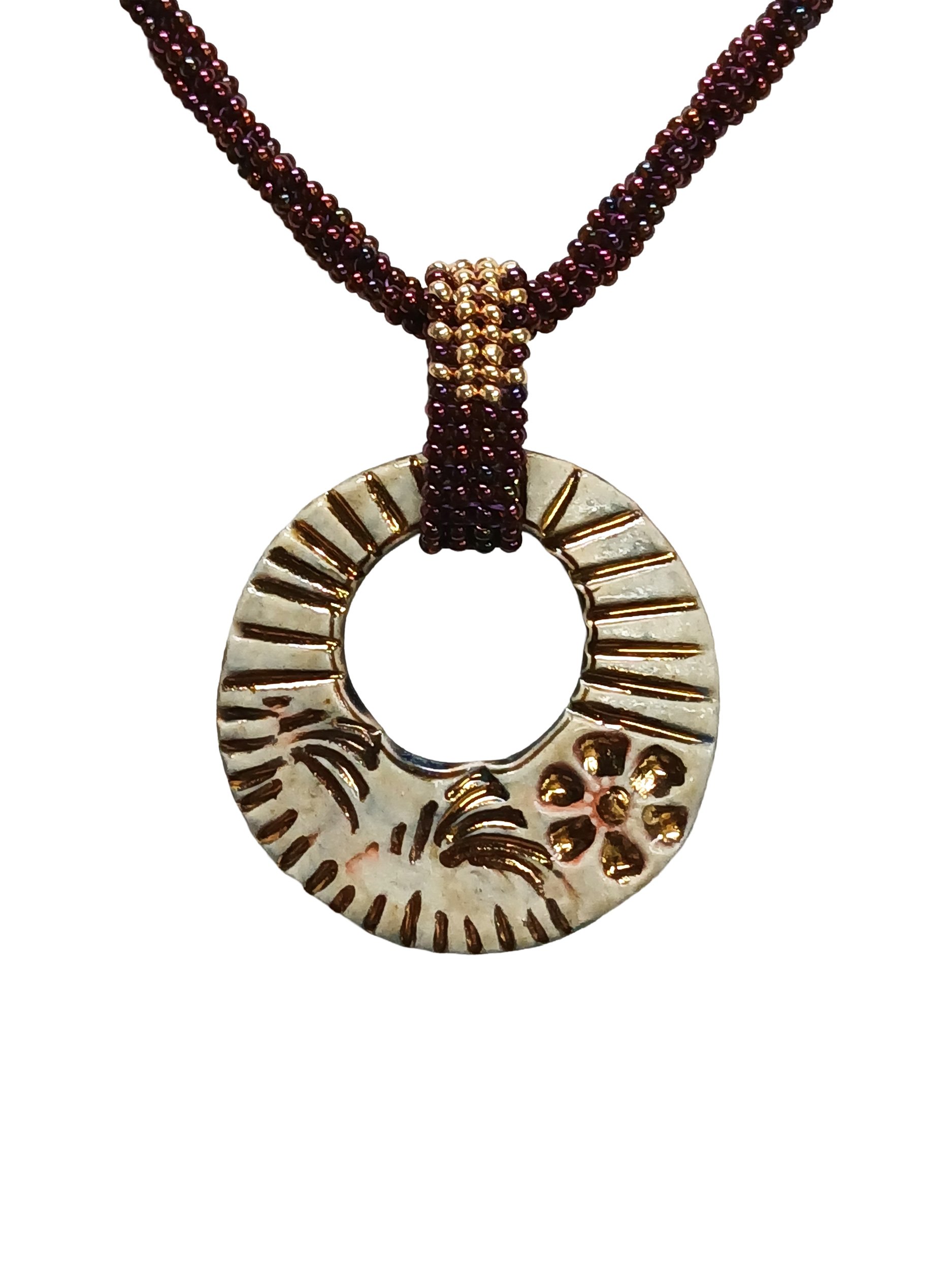 Handmade non-metal beaded rope necklace with open round pendant handwoven in metallic iris rose and gold accents and toggle clasp.