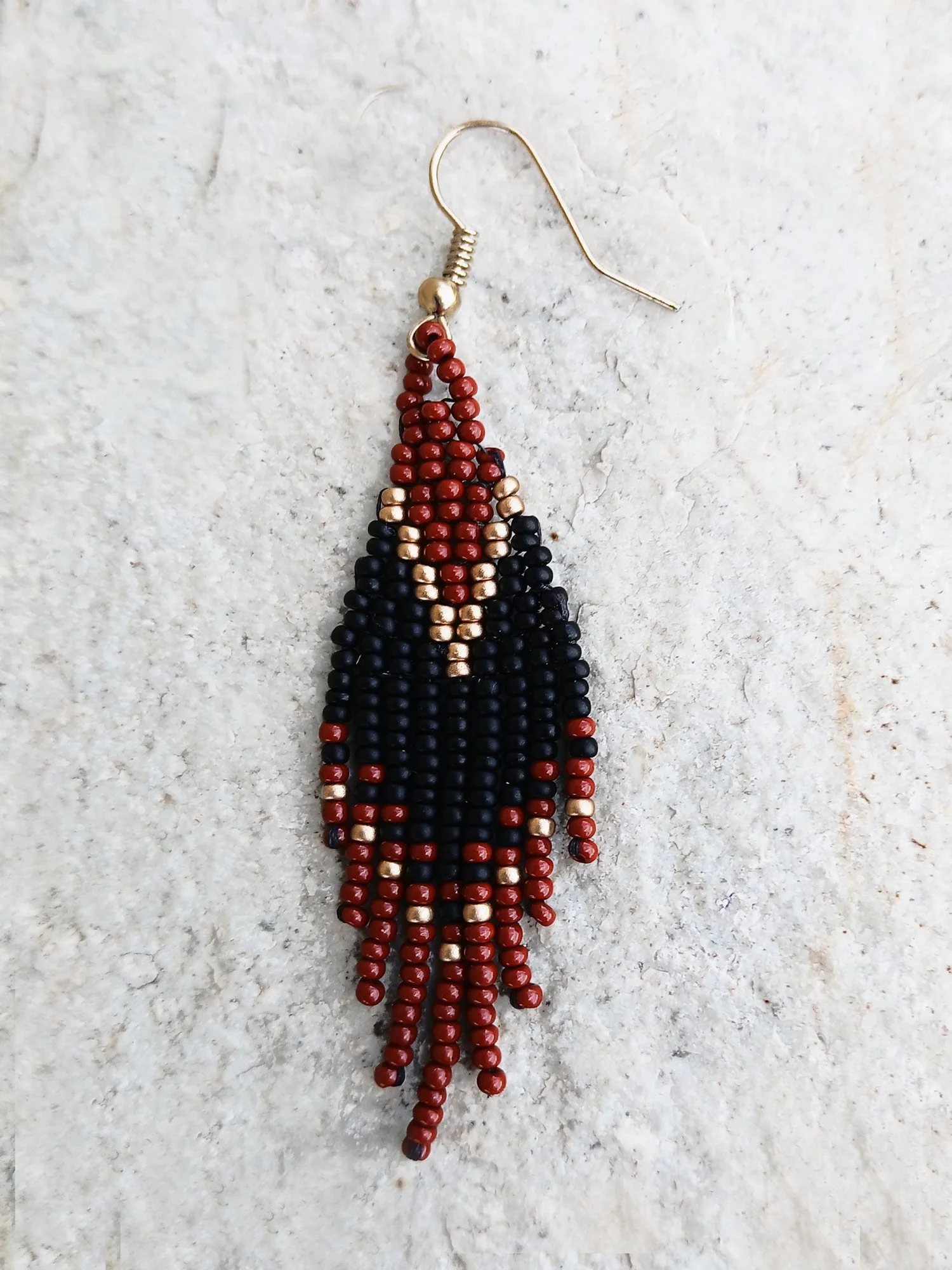 Handwoven brick-stitch beaded earrings in medium rust brown, black, and gold with a short fringe design.