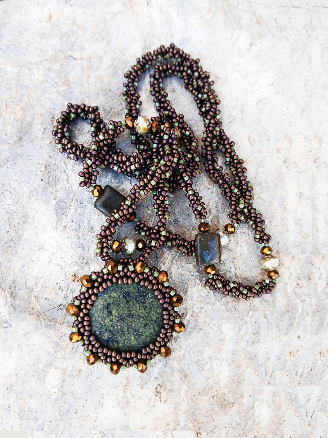 Handmade statement pendant necklace featuring a natural forest green agate gemstone wrapped in handwoven beaded bezel with a brown and bronze chain.
