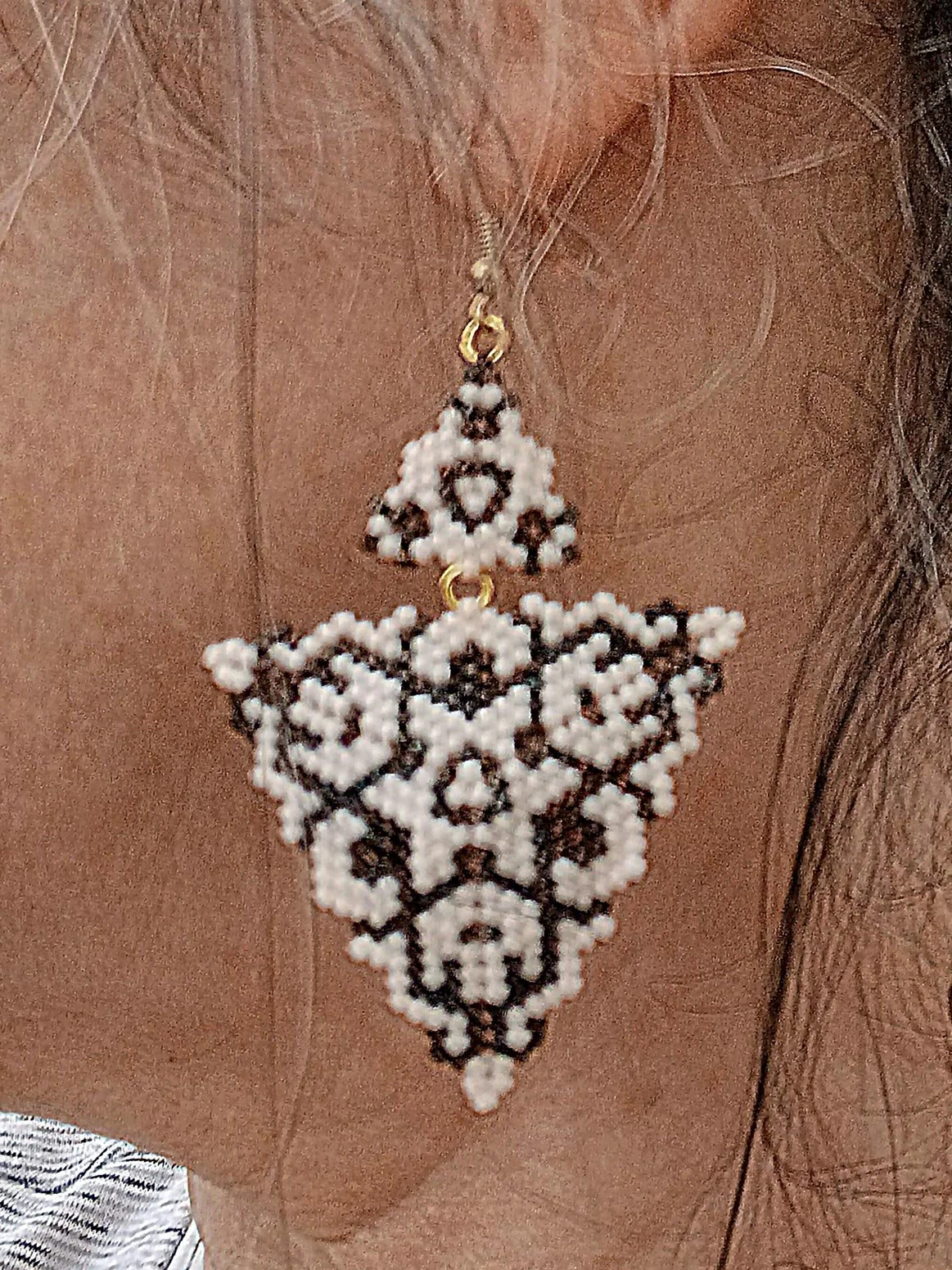Handmade copper brown and alabaster white geometric triangle drops with two triangles beaded earrings in handwoven in peyote stitch design on model.