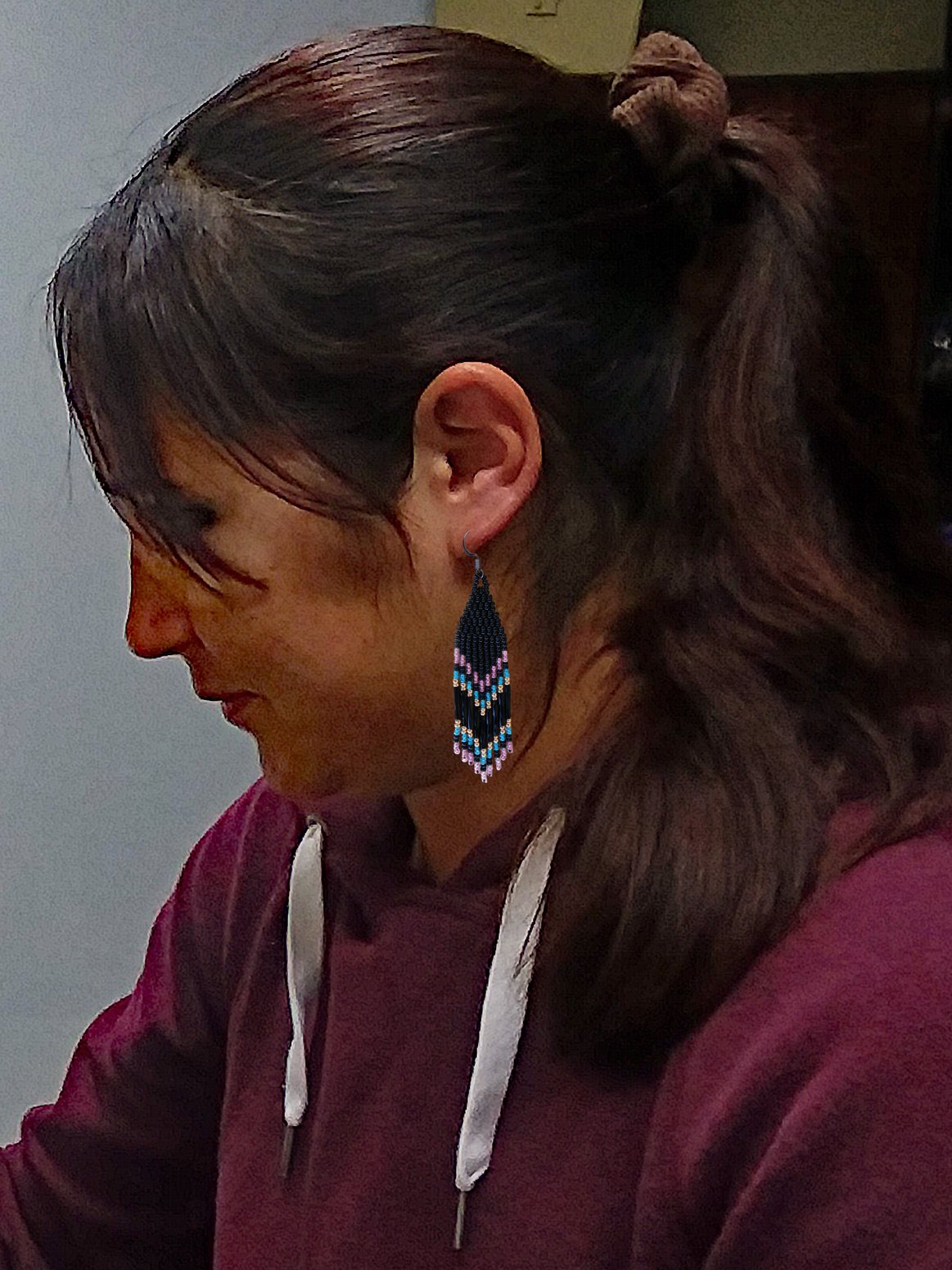 Model wearing colorful beaded fringe earrings with pink, orchid, and turquoise details