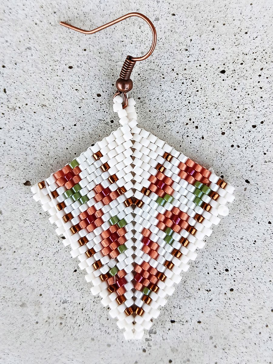 Elegant handmade geometric kite drop beaded earrings handwoven with a soft ivory and peach floral pattern and shimmering metallic gold accents.
