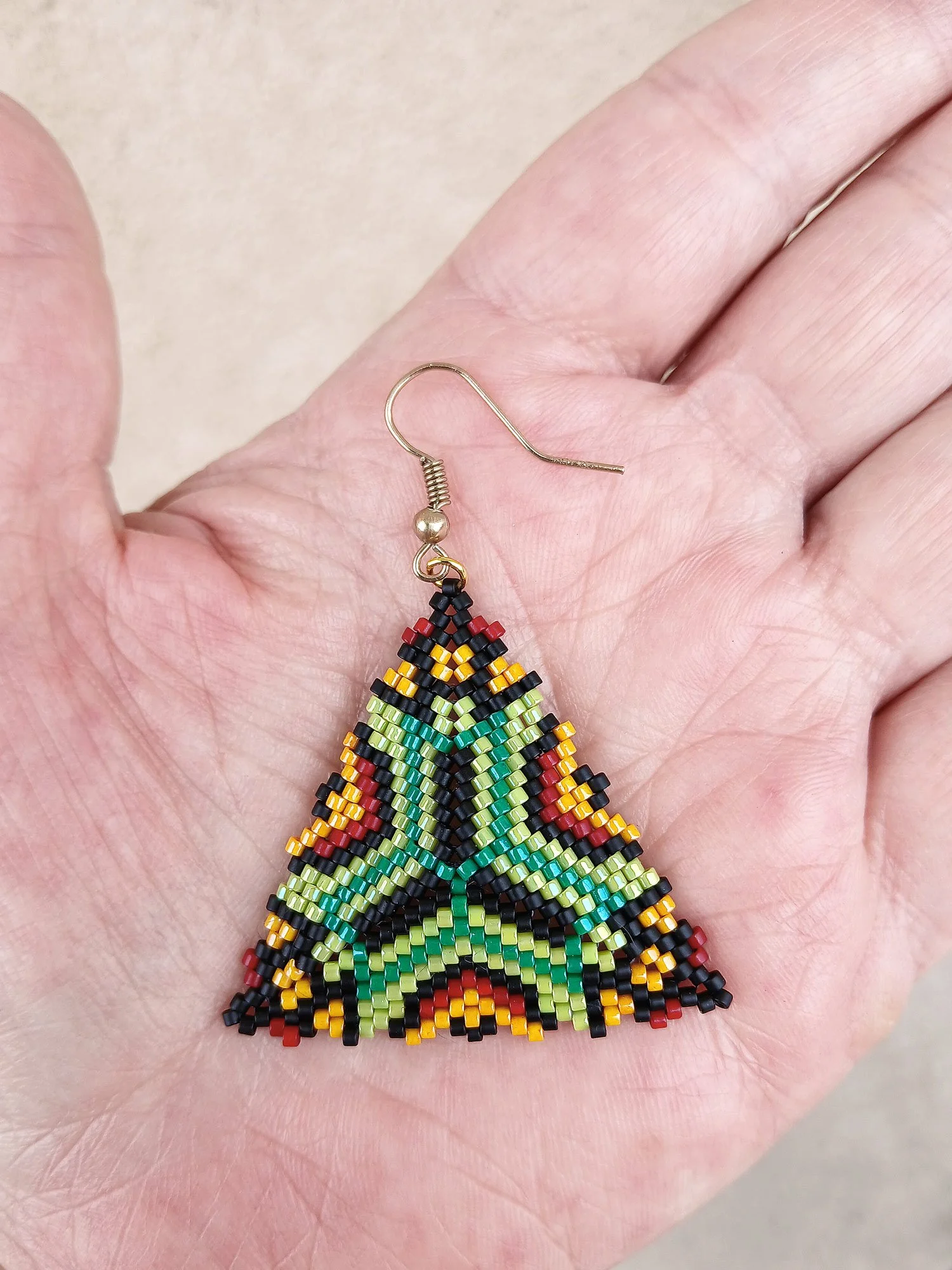 Handmade southwestern geometric triangle peyote beaded dangle earrings featuring a handwoven in green, red, black, and orange color palette.