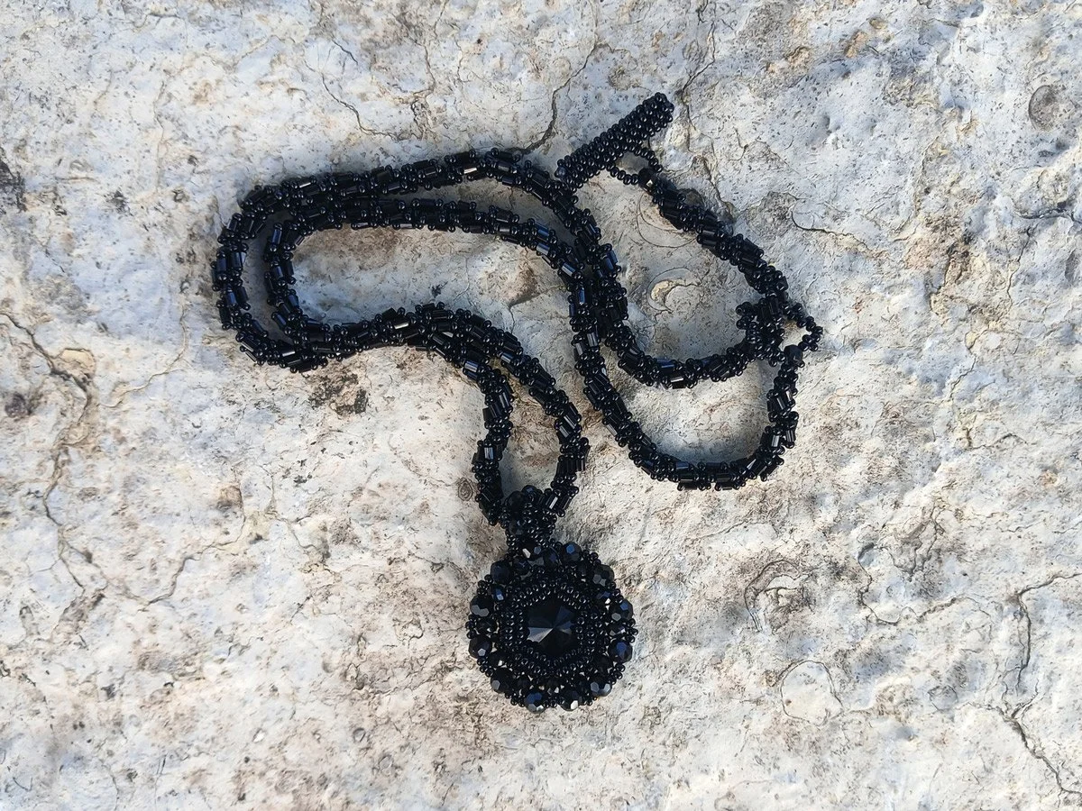Handmade statement pendant necklace featuring a sparkling black Rivoli crystal focal point handwoven with a matching seed bead chain.