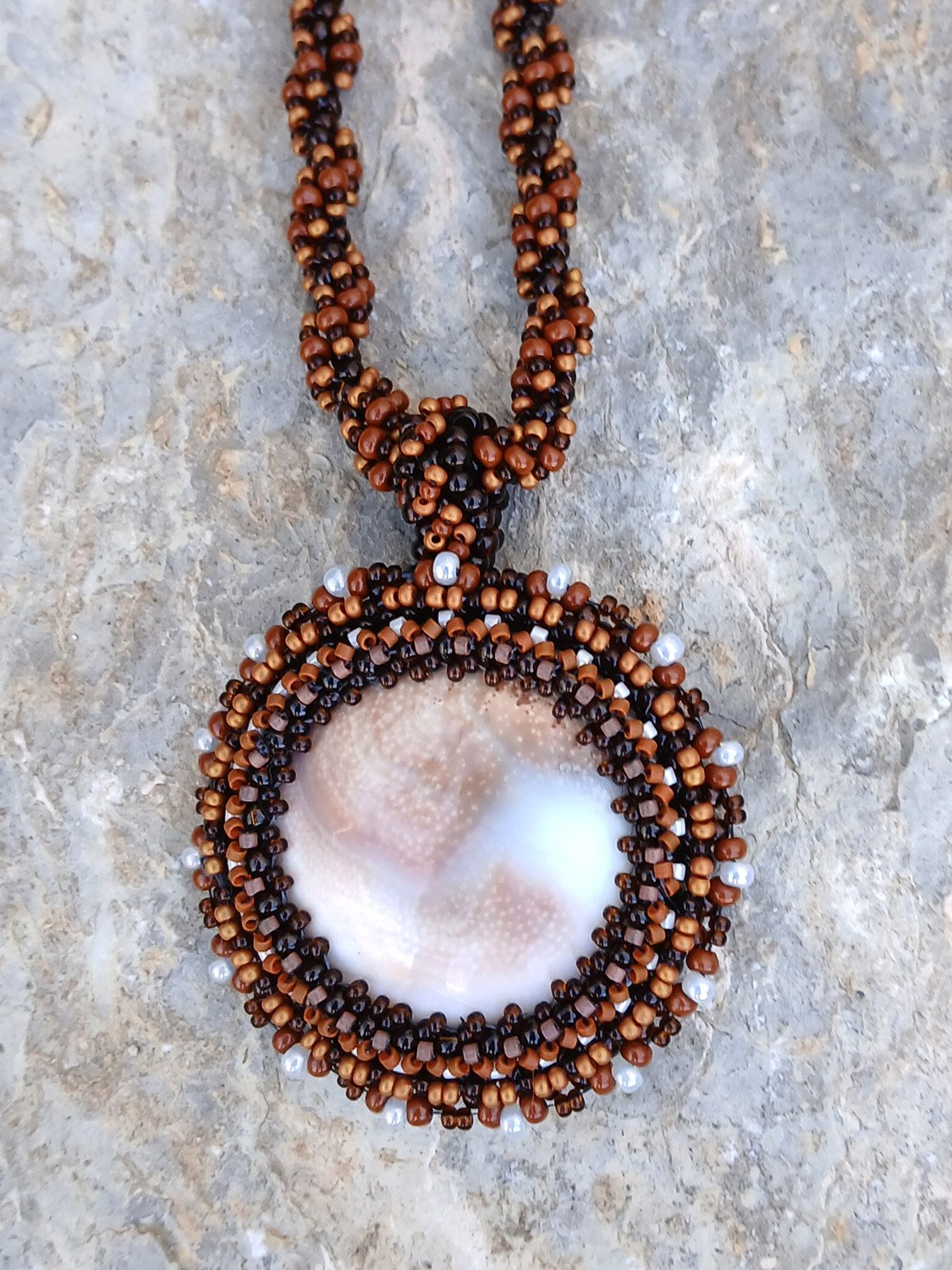 Handmade nature-inspired beaded necklace featuring a beaded bezel on natural spiral Shiva snail shell pendant handwoven in brown and white seed beads.
