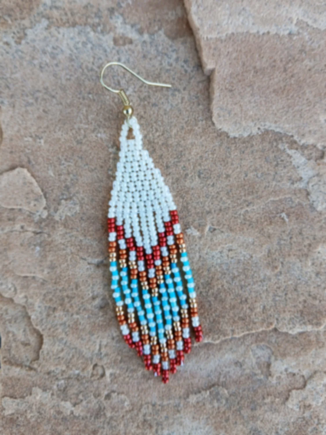 Handmade Southwestern beaded fringe dangle earrings handwoven in an ivory white, red, gold, orange, and blue desert sunset color palette.