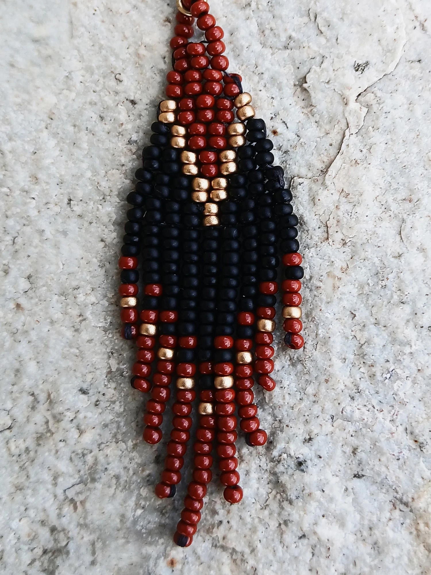 Handwoven brick-stitch beaded earrings in medium rust brown, black, and gold with a short fringe design.