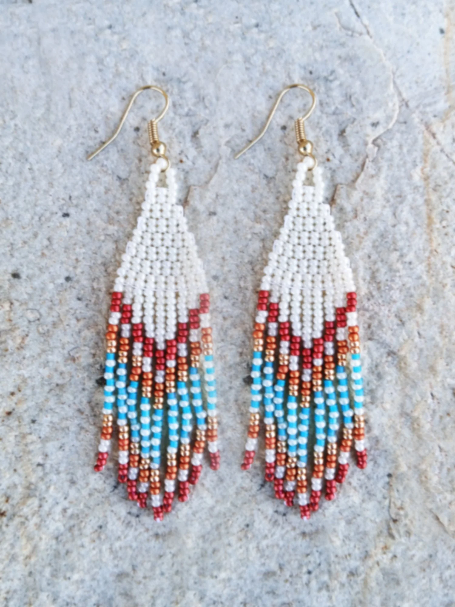Handmade Southwestern beaded fringe dangle earrings handwoven in an ivory white, red, gold, orange, and blue desert sunset color palette.