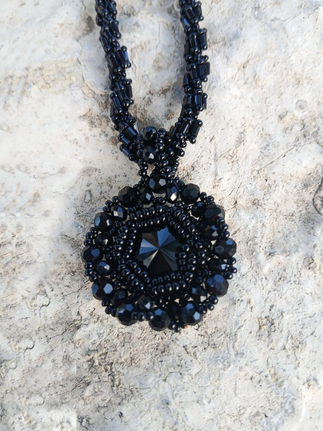 Handmade statement pendant necklace featuring a sparkling black Rivoli crystal focal point handwoven with a matching seed bead chain.