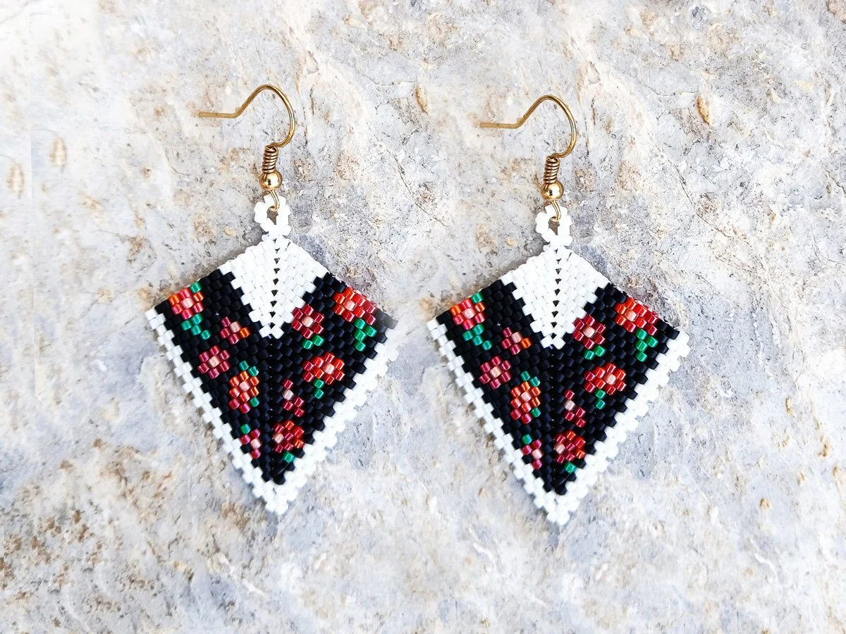 Elegant handmade geometric kite drop beaded earrings handwoven with an intricate black and white band pattern and a striking red floral motif.