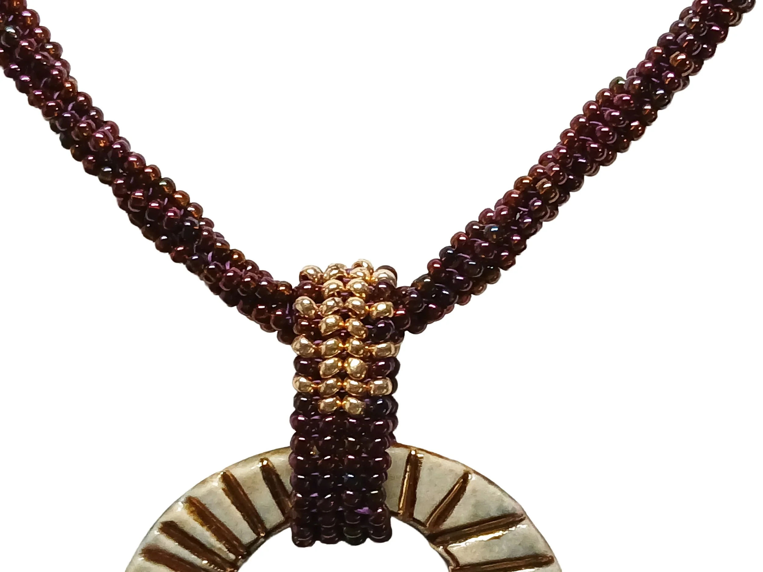 Handmade non-metal beaded rope necklace with open round pendant handwoven in metallic iris rose and gold accents and toggle clasp.