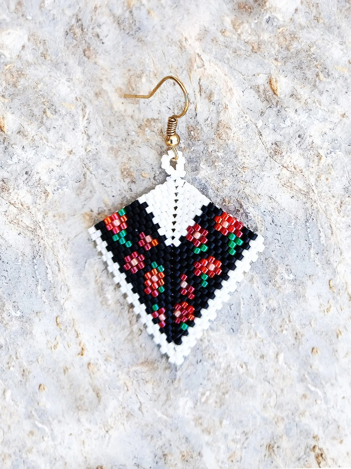 Elegant handmade geometric kite drop beaded earrings handwoven with an intricate black and white band pattern and a striking red floral motif.