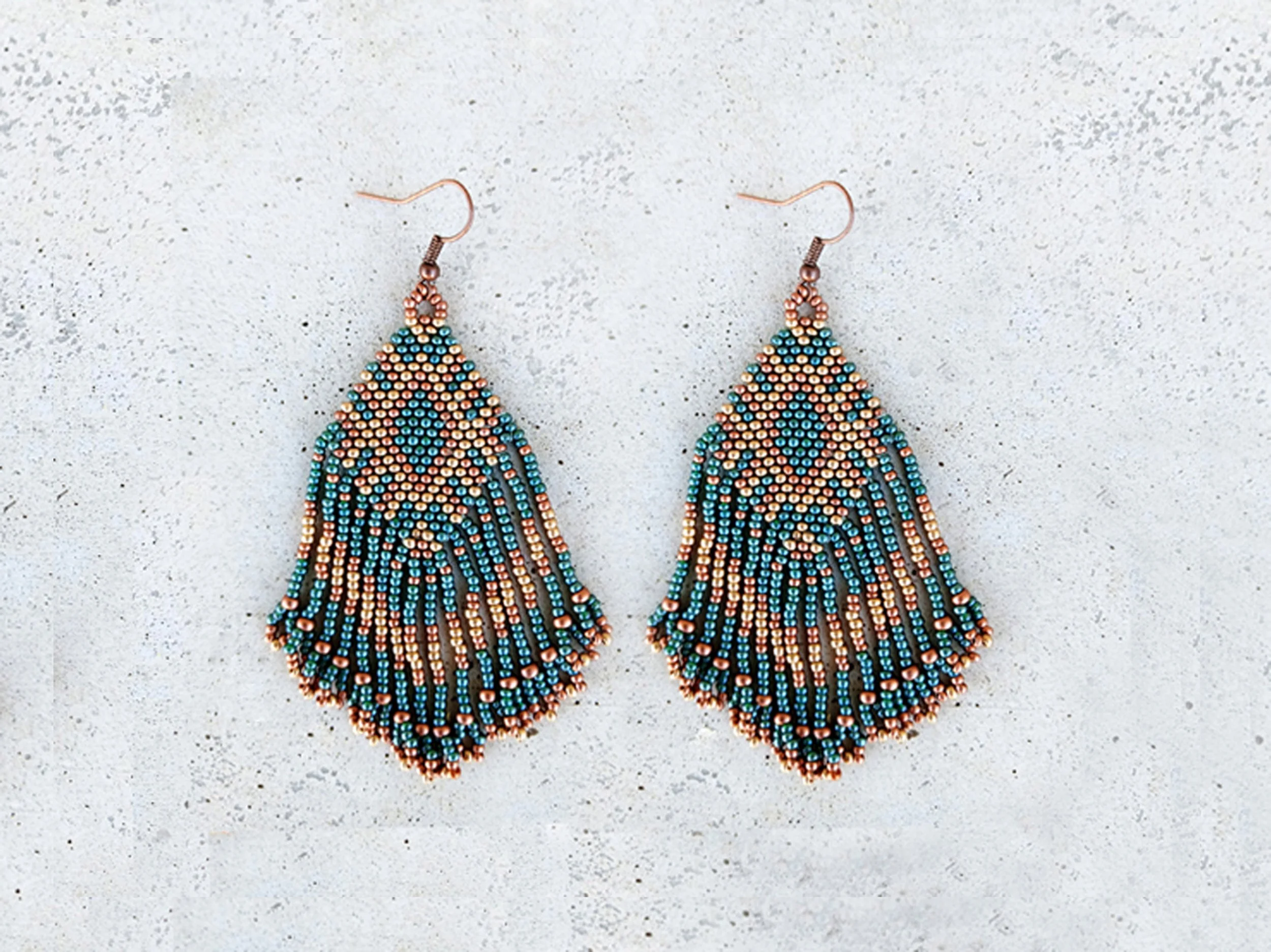 Medium-length beaded fringe earrings with metallic bronze, gold, and green seed beads in a tribal geometric pattern