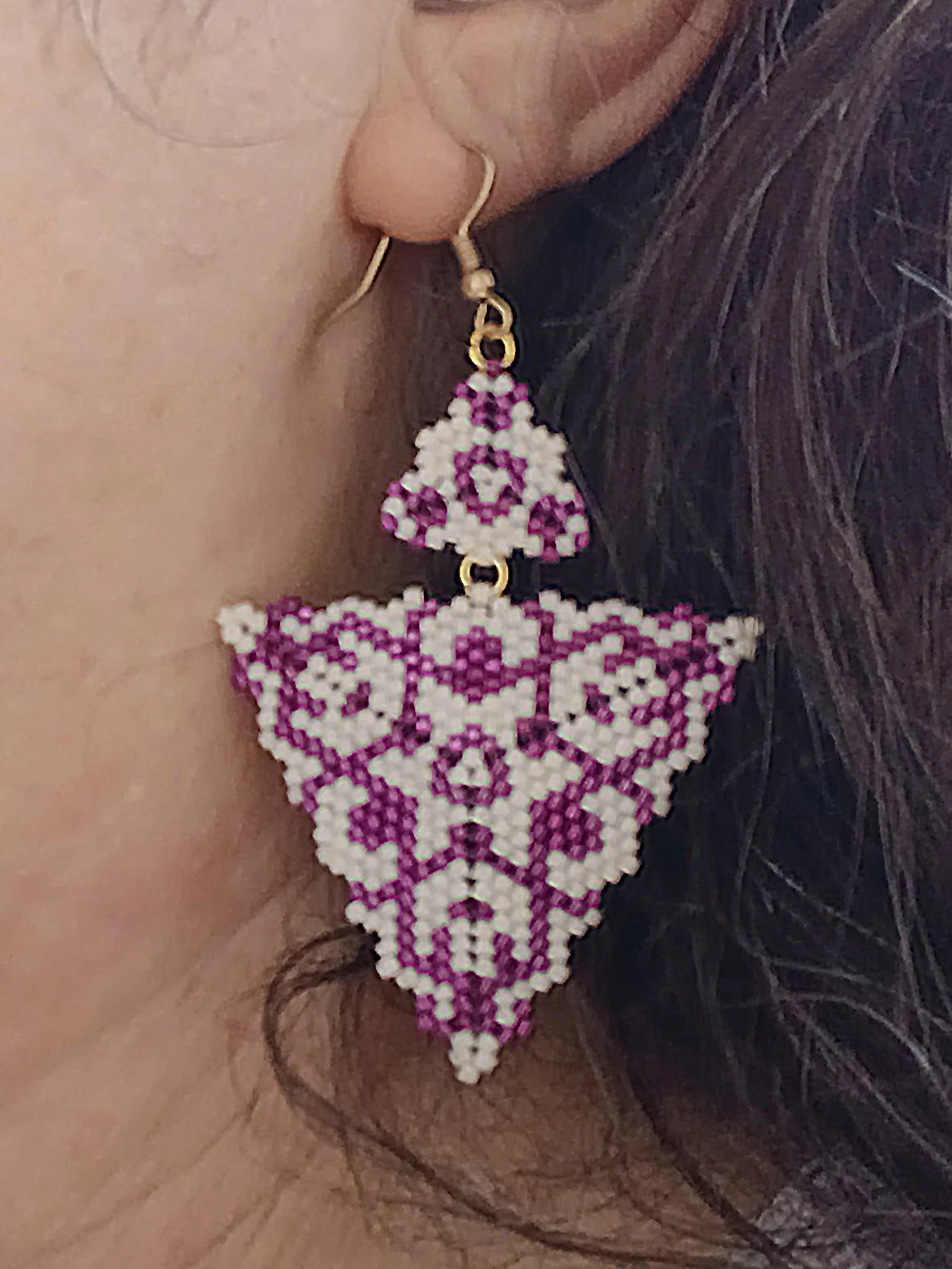 Handmade purple and alabaster white geometric triangle drops with two triangles beaded earrings in handwoven in peyote stitch design on model.