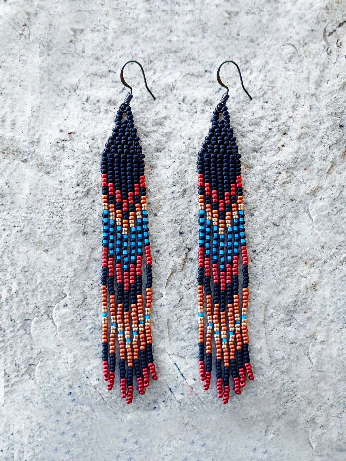 Handmade Southwestern beaded long fringe dangle earrings handwoven in a dramatic black, red, blue, gold, and copper mountain sunset color palette.