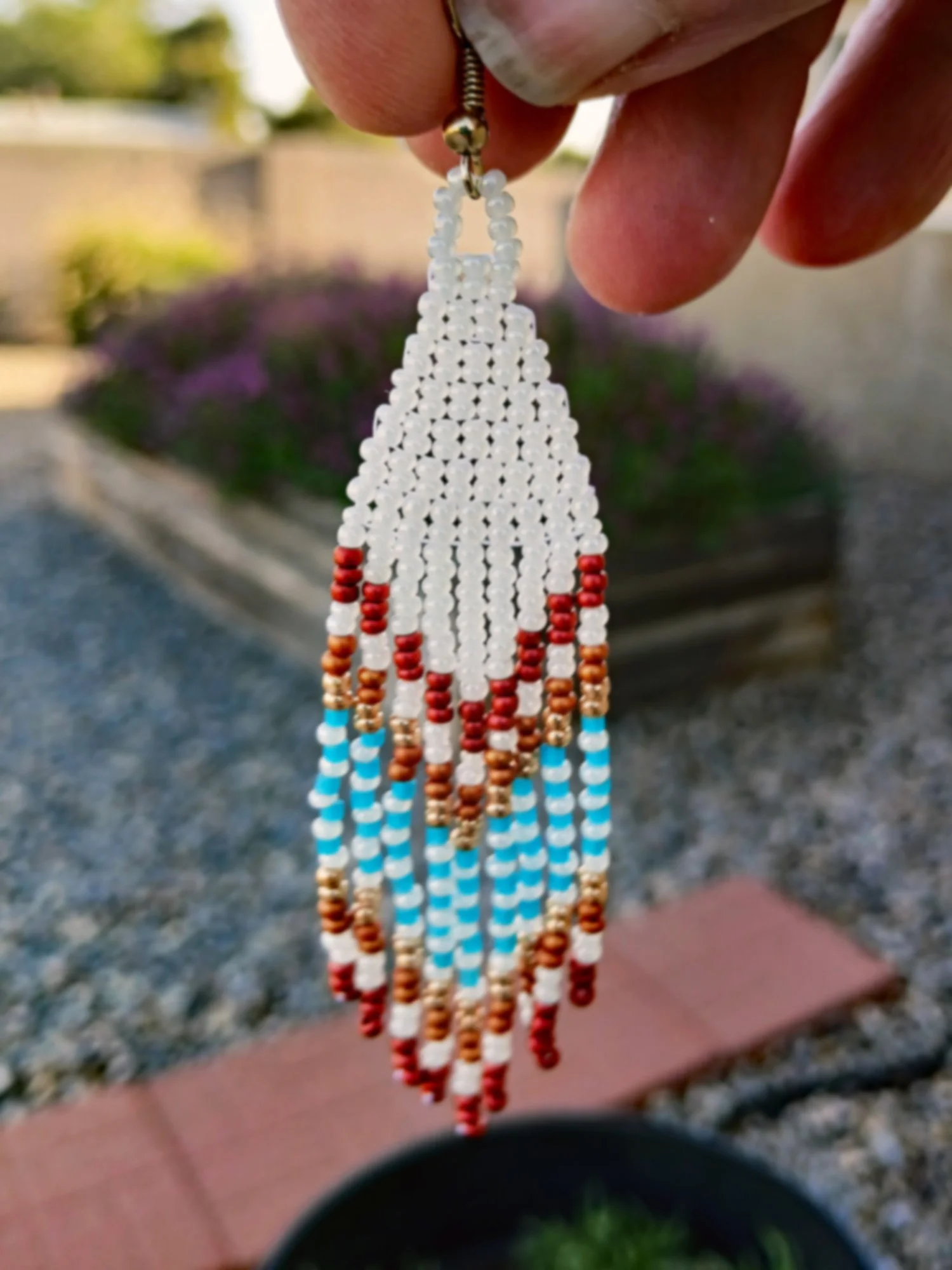 Handmade Southwestern beaded fringe dangle earrings handwoven in an ivory white, red, gold, orange, and blue desert sunset color palette.