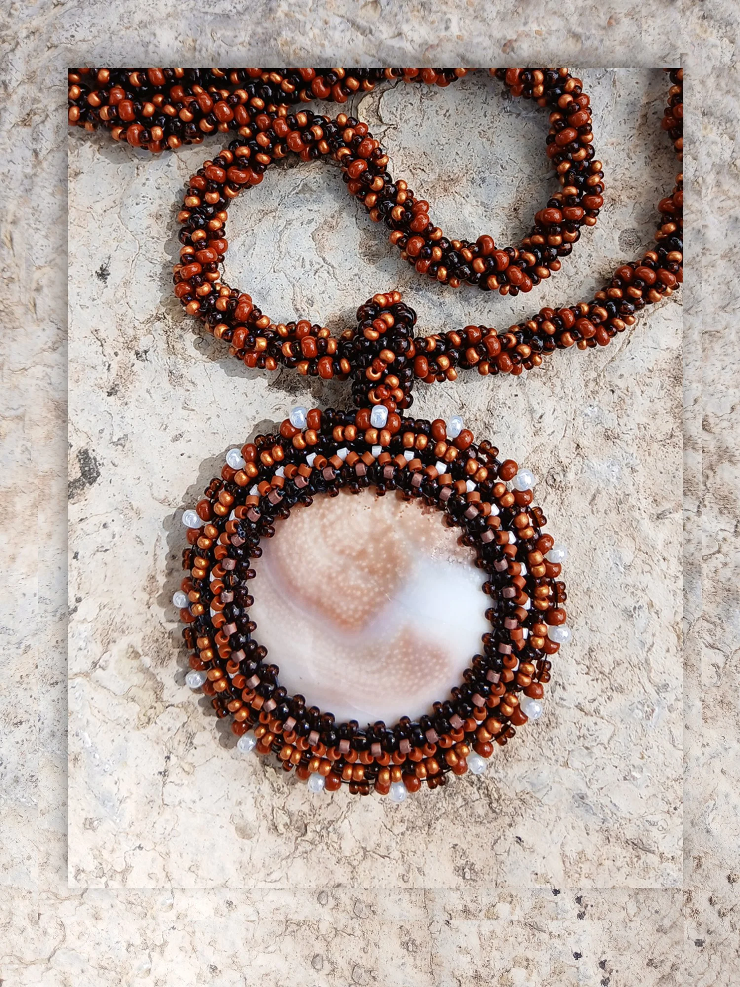 Handmade Boho-style necklace with a natural spiral Shiva eye shell pendant on a seed bead chain