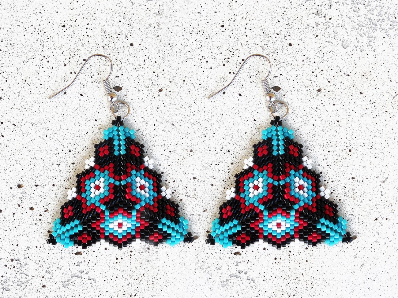 Handmade geometric triangle beaded earrings featuring a handwoven peyote-stitch hanging dangle design in blue, red, black, and white.