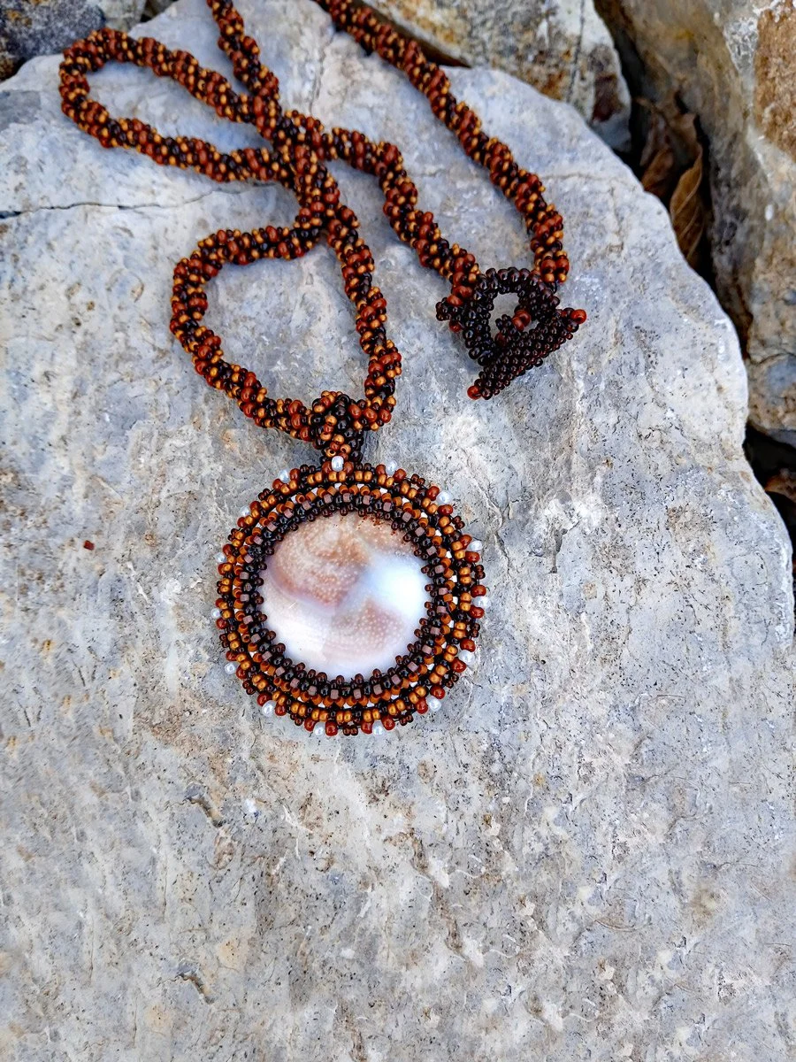 Handmade nature-inspired beaded necklace featuring a beaded bezel on natural spiral Shiva snail shell pendant handwoven in brown and white seed beads.