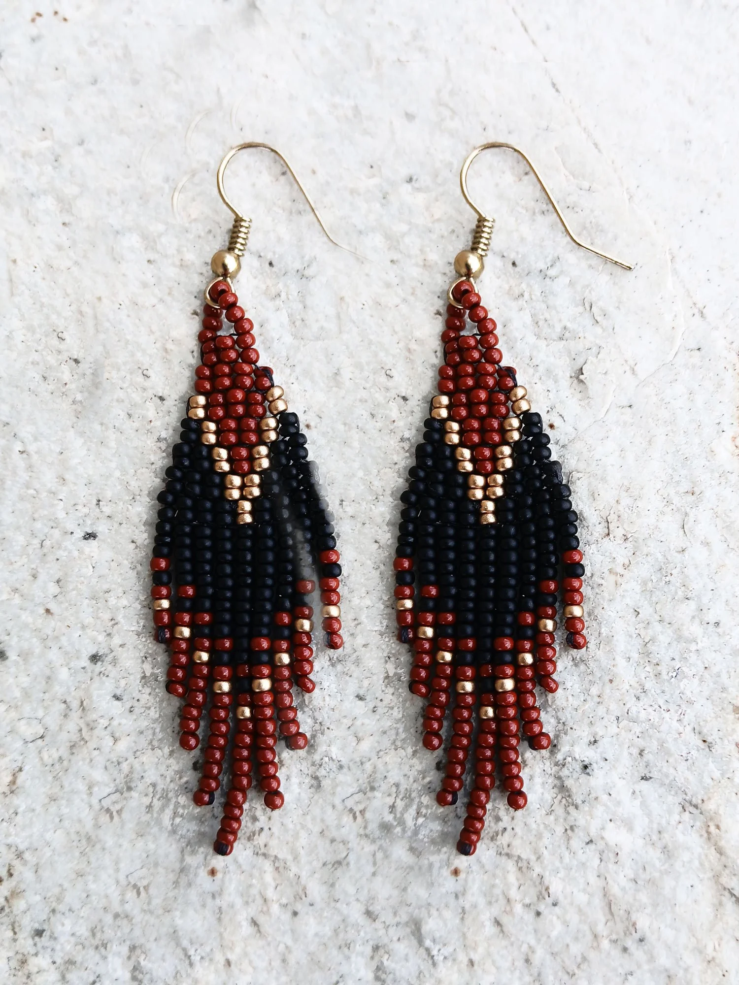 Handwoven brick-stitch beaded earrings in medium rust brown, black, and gold with a short fringe design.