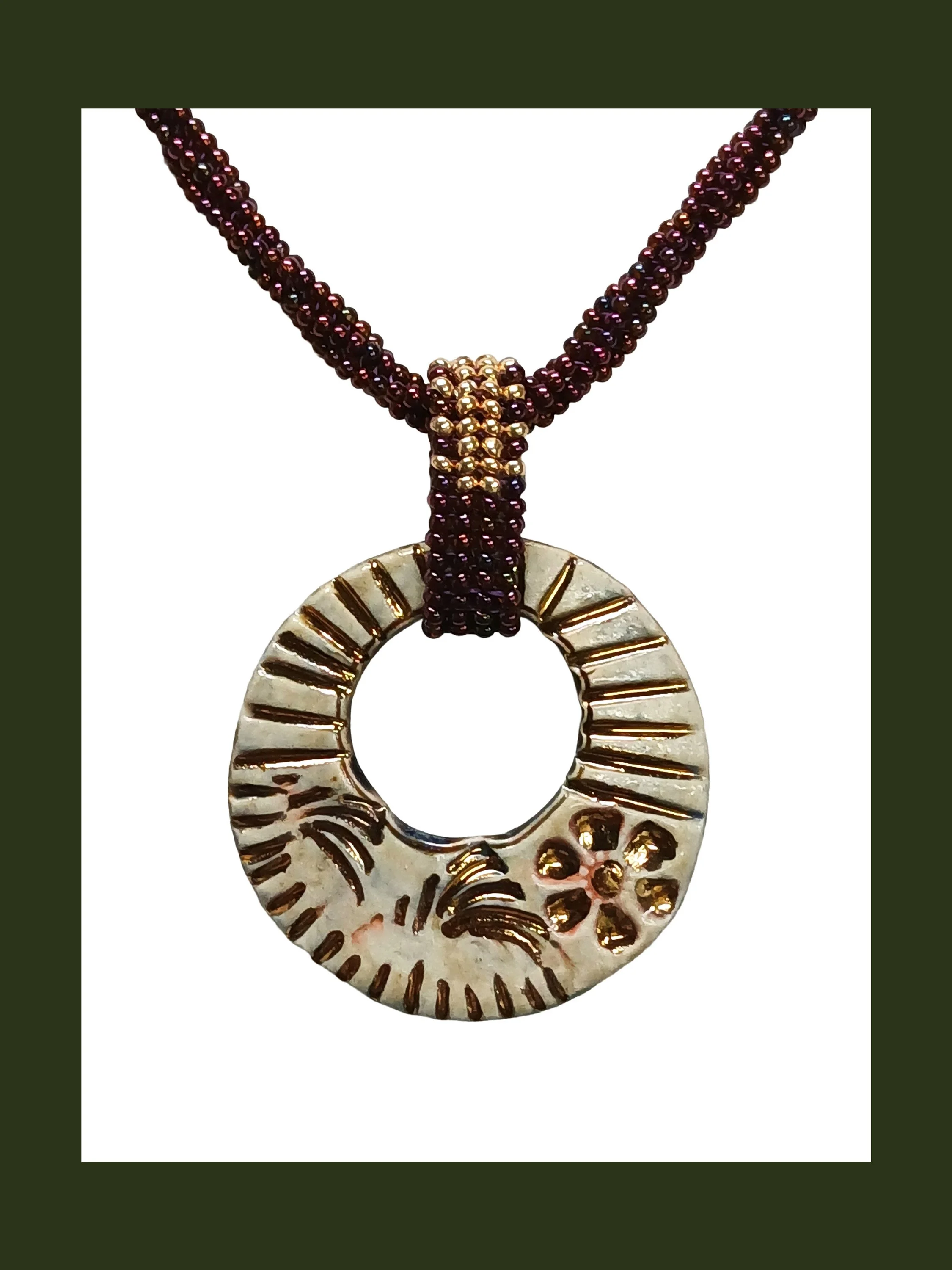 Handmade non-metal beaded rope necklace with open round pendant handwoven in metallic iris rose and gold accents and toggle clasp.