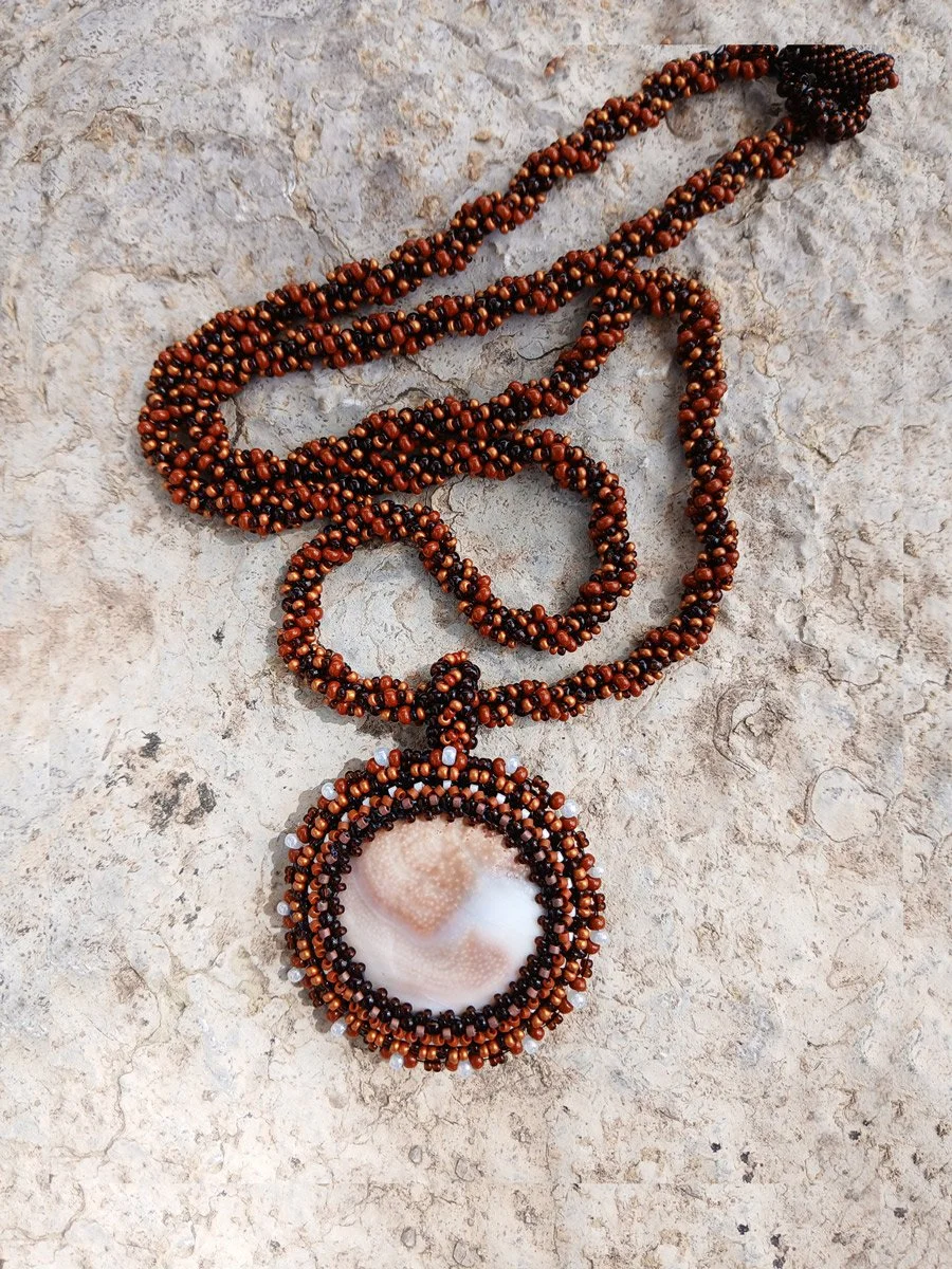 Handmade nature-inspired beaded necklace featuring a beaded bezel on natural spiral Shiva snail shell pendant handwoven in brown and white seed beads.