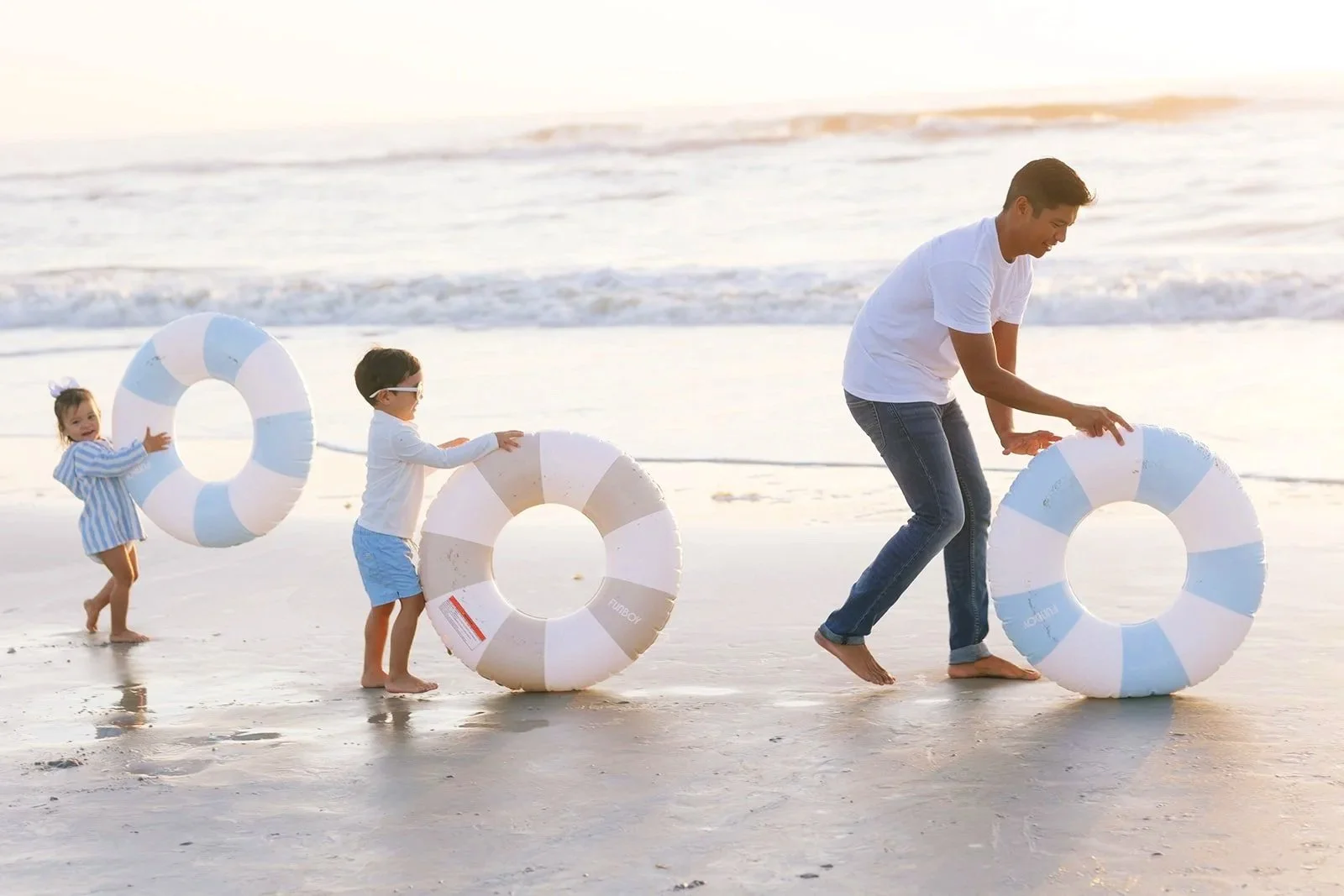 Dr. Noah Andone playing on the beach at sunrise with his two young children