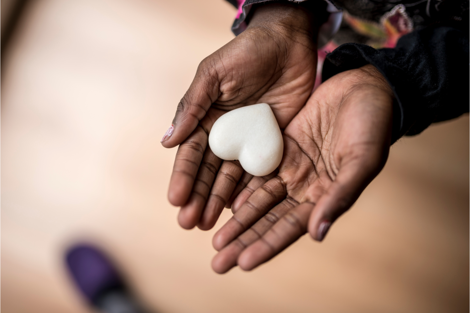 Person holding a white heart-shaped stone in their hand.