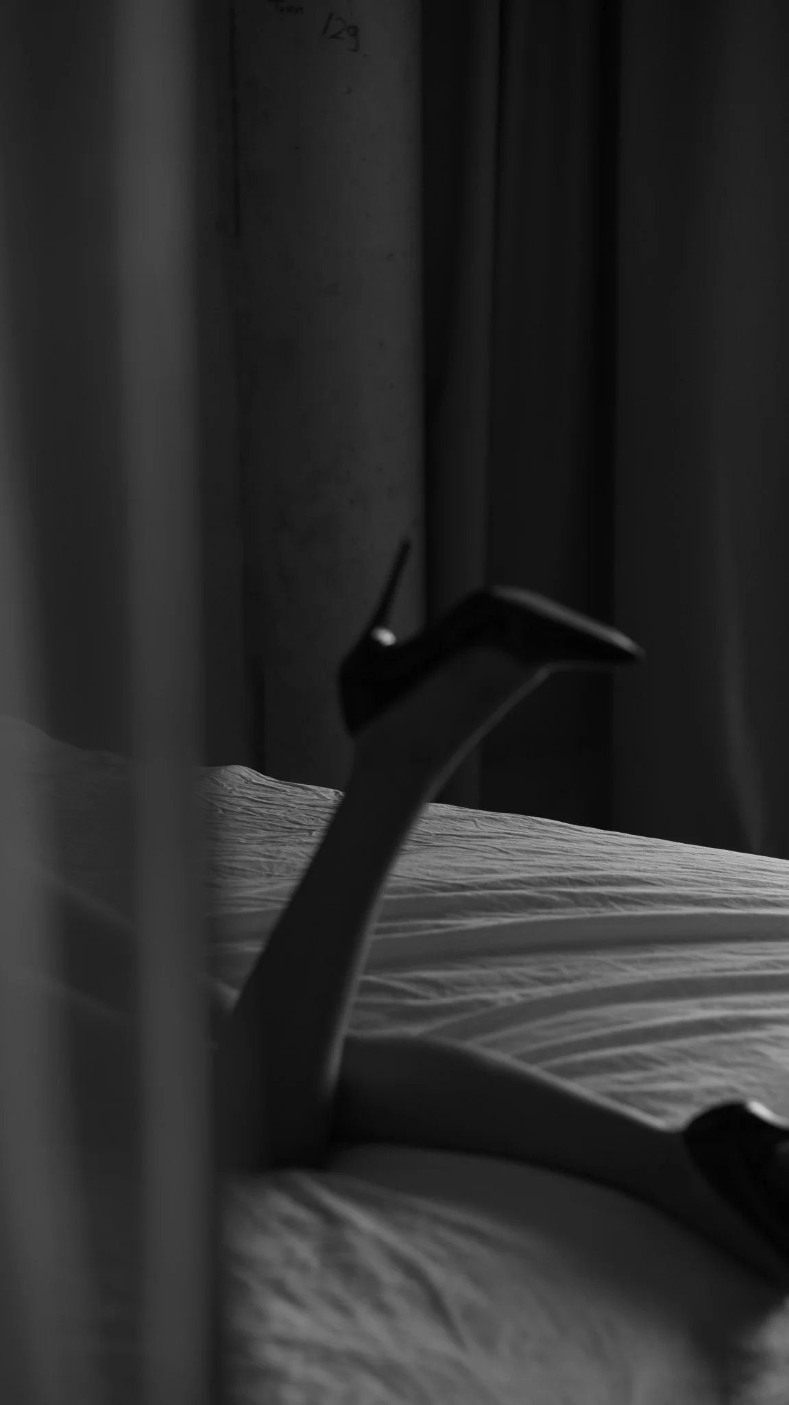 Beine angewinkelt mit Highheels, im Hintergrund schwarze Vorhänge.