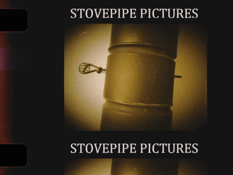 Black and white photo of a stovepipe with a small key hanging from its side, with The words 'Stovepipe Pictures' at the top and bottom of the image.