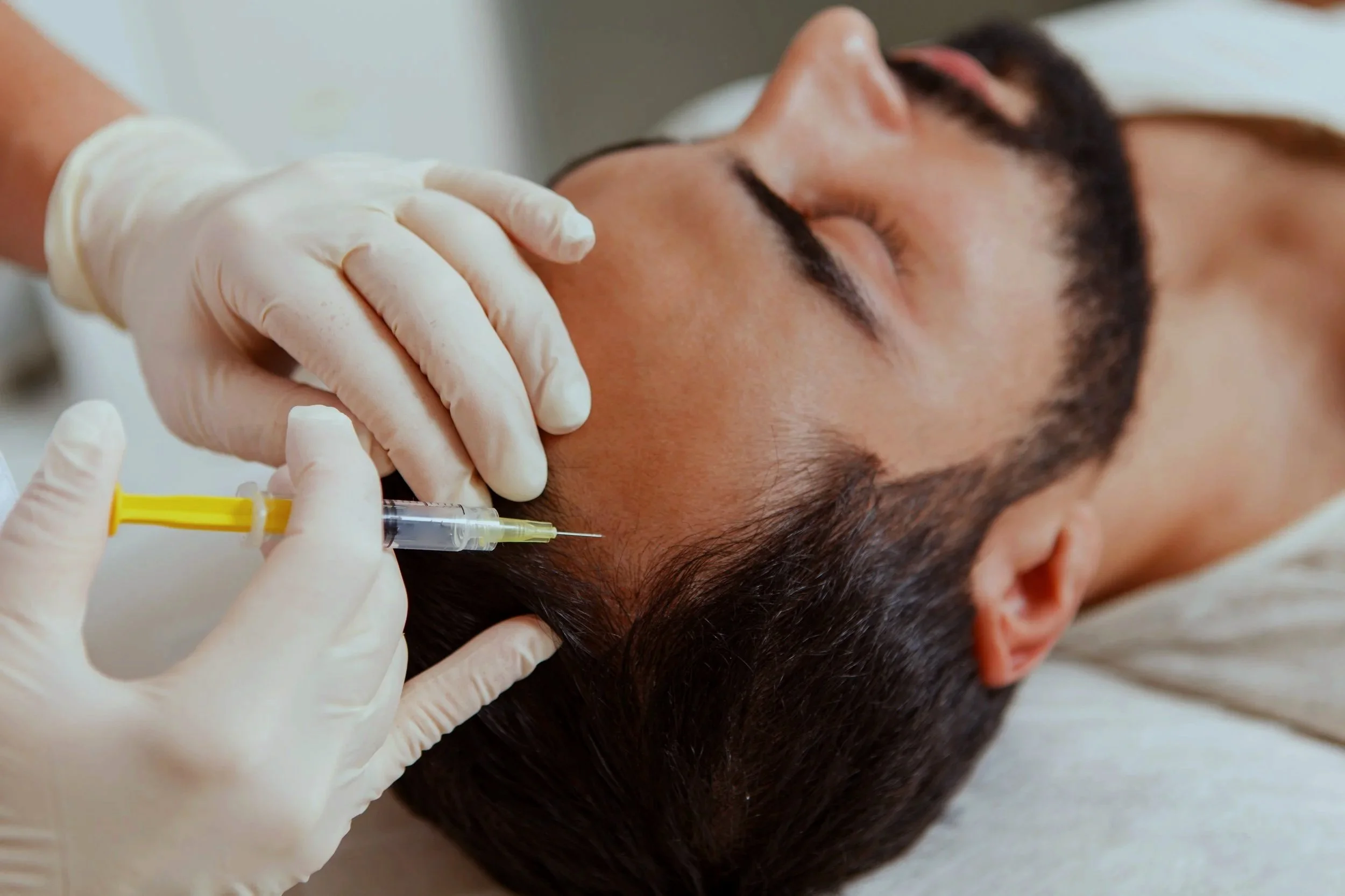Person receiving a medical injection in the neck area from a healthcare professional wearing gloves.