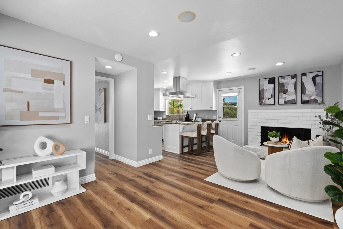 The left wall was the only blank stretch in the open half of the house, so it takes a large framed piece with a low console beneath and a few things on top. It gives that side something to do without narrowing the walkway, and it lets the fireplace a