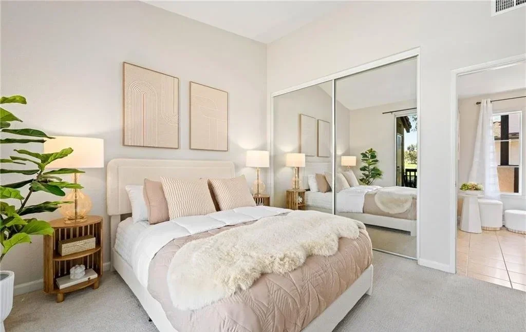 The mirrored closet wall is the feature here, so the bed is dressed light and kept low to give it something worth doubling. Two matching lamps hold the corners and the walkway stays clear on both sides, which is what makes the only bedroom in the uni