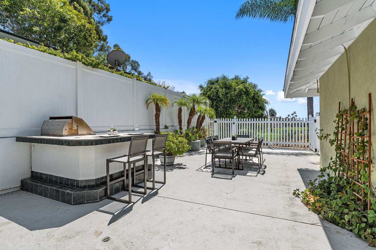 The built-in bar was already here. Two stools pulled up to it turn a masonry counter into somewhere to sit, and from this end the dining set reads against the fence line instead of the pool.