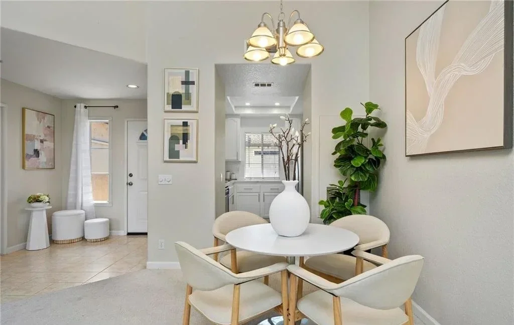 A round pedestal table was the only way to seat four here and still leave room to pass behind the chairs. One oversized canvas does the work of a gallery wall, and the centerpiece stays low so the line through to the kitchen never closes.
