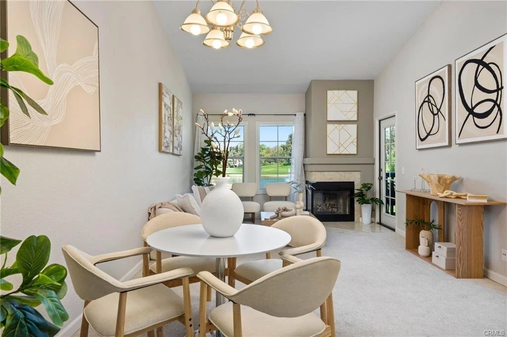 Coordinated furnishings establish a seamless transition between the dining and living areas, showcasing the home's open layout and versatility. Warm neutrals, natural textures, and subtle greenery create a cohesive, sophisticated presentation.