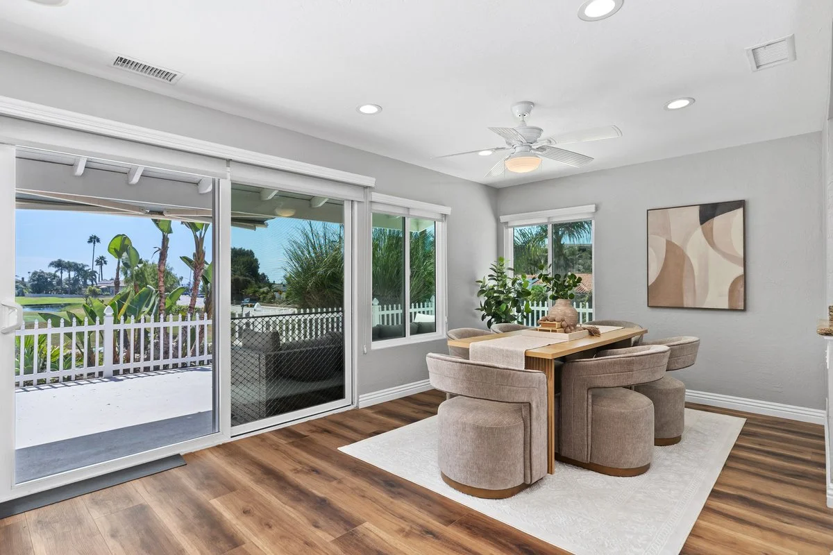 Barrel chairs on low plinth bases leave the slider wall uninterrupted when you look across the room. The table is dressed with almost nothing, because anything tall here would sit directly in front of the one thing this room has going for it.