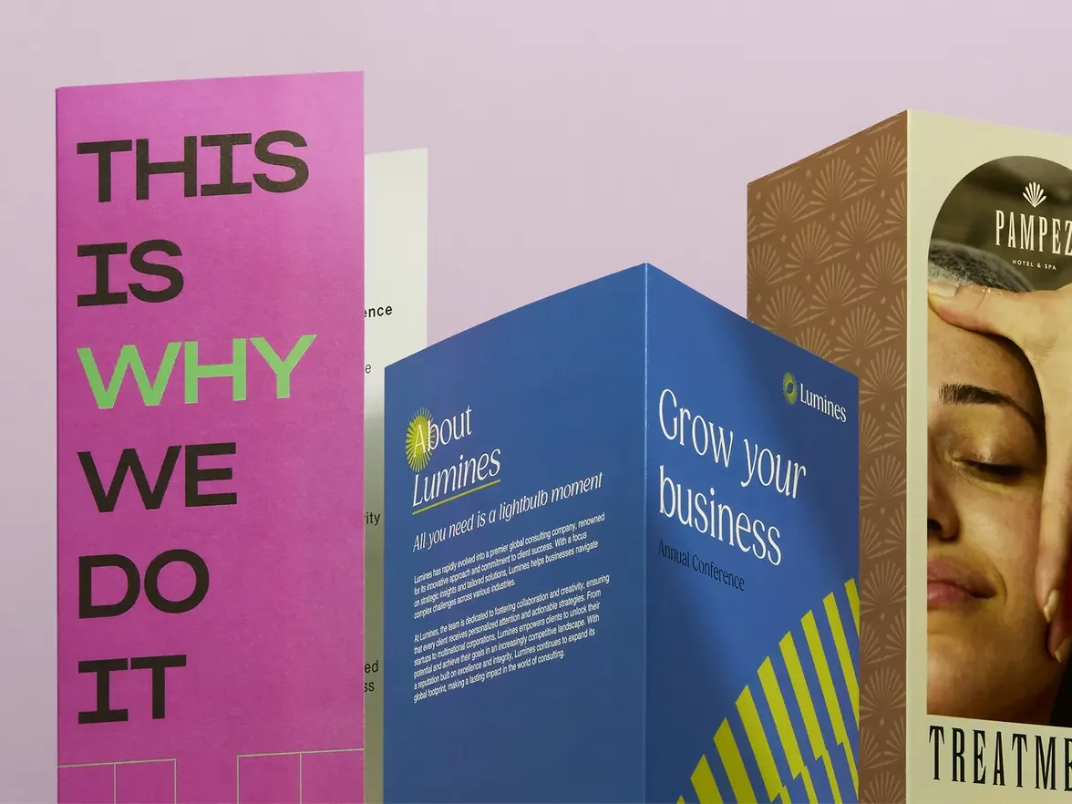 Colorful informational display boards at a conference, including a bright pink board with bold black and green lettering reading 'This is why we do it', and a blue board with white text about Lumines' business growth and annual conference.