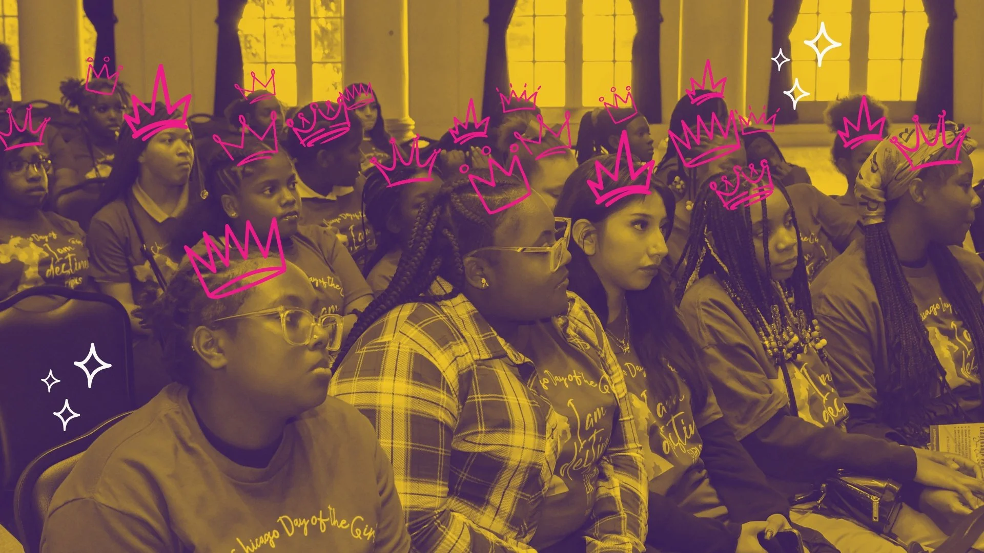 Group of women and girls attending an indoor event, some wearing glasses and casual clothing, with pink crown doodles drawn over their heads.