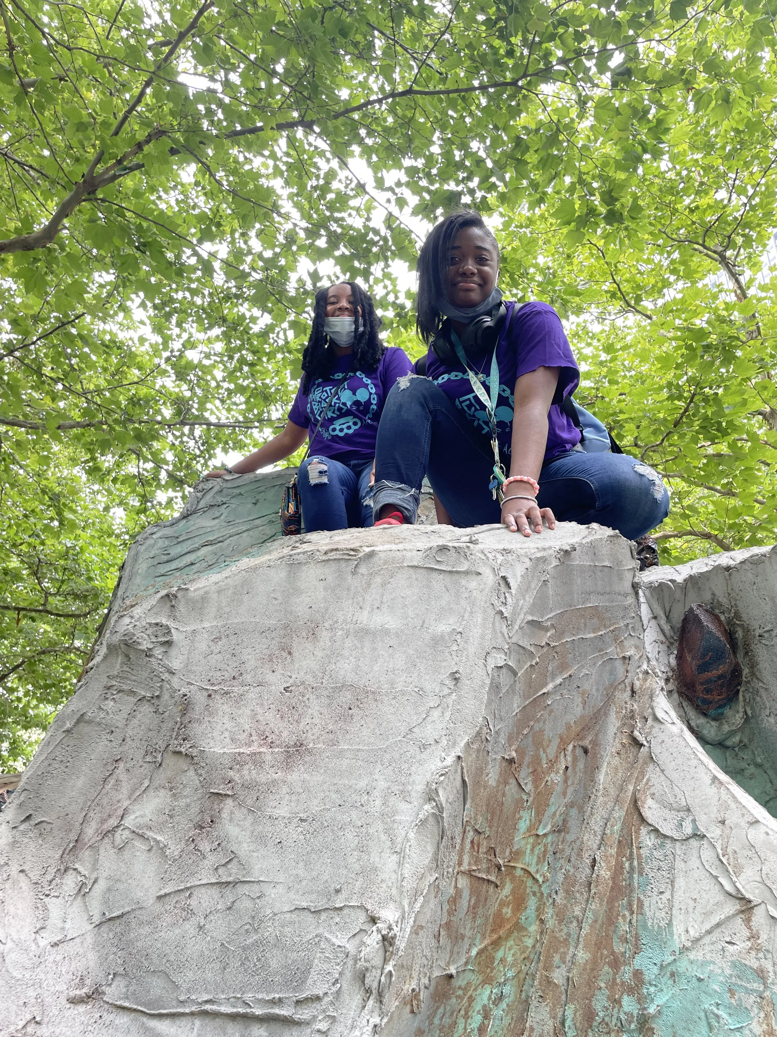 Two young girls climbing a rock
