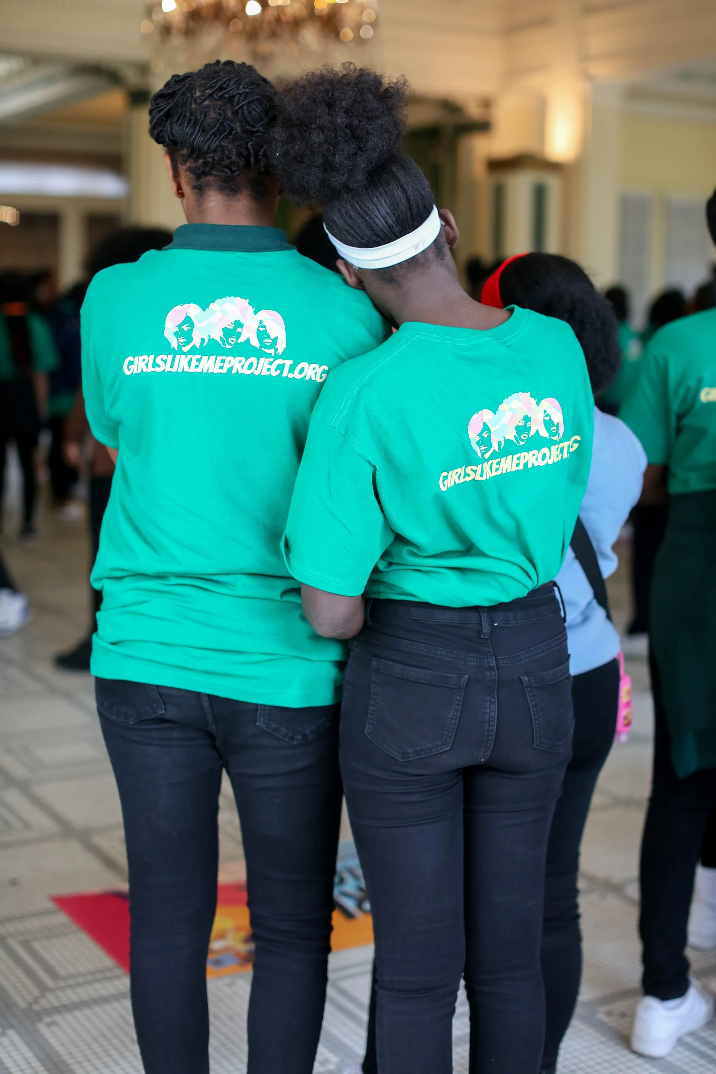 Two girls standing together with GLMPI shirts on.