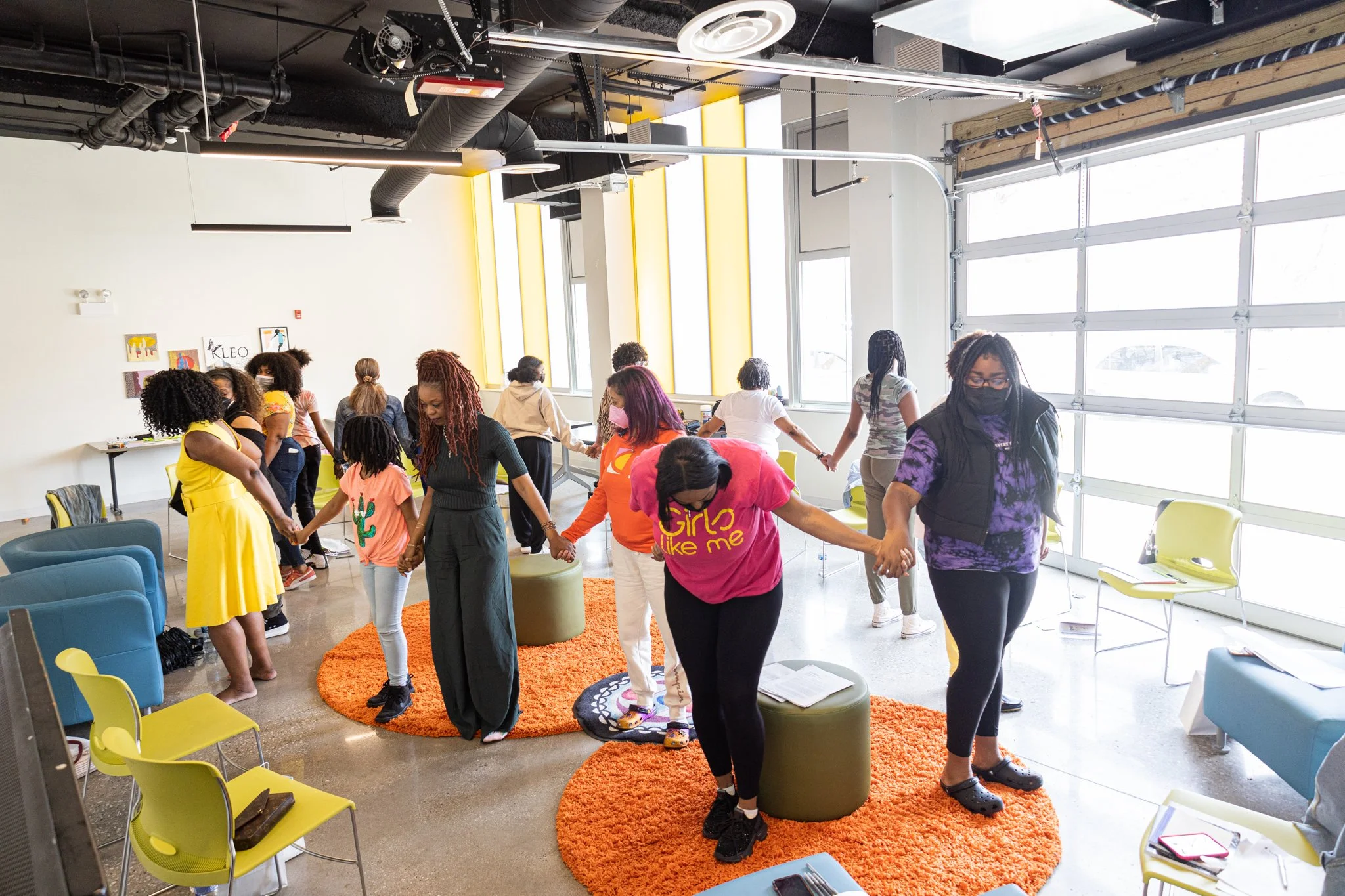 Circle of women and young girls holding hands.