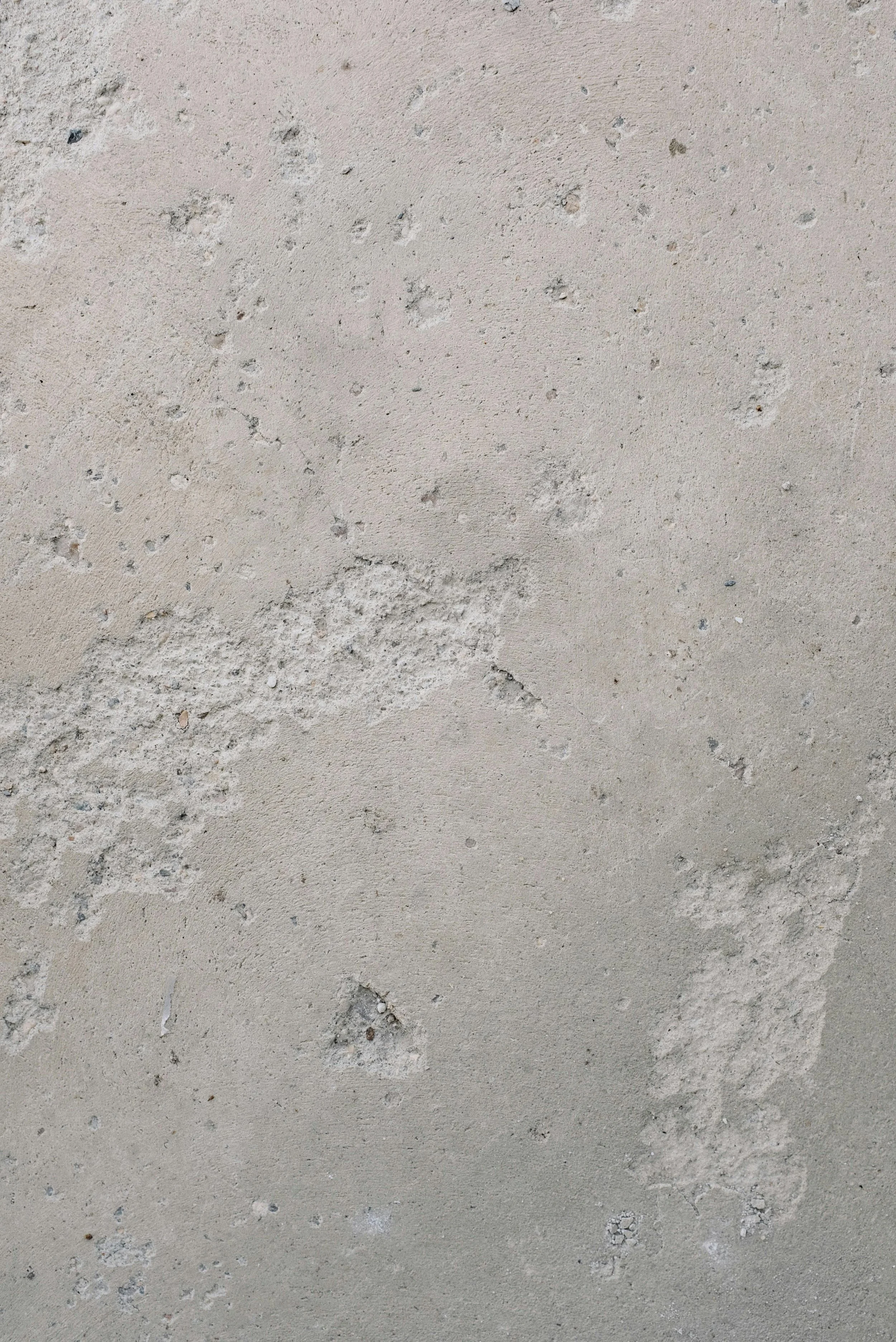 Close-up image of a sandy surface with small pebbles and patches of textured material.