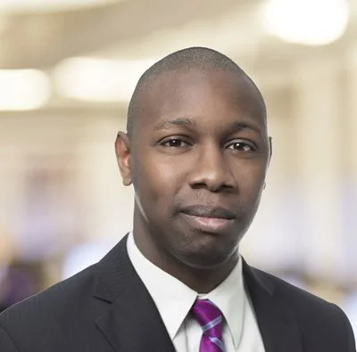 A professional man wearing a suit and tie in an indoor setting.