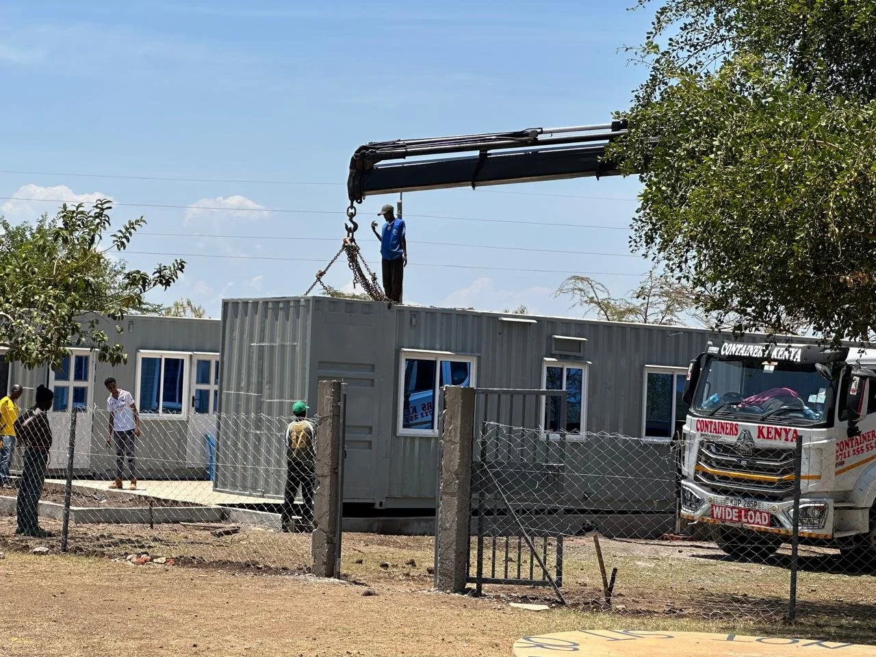 A crane lowering a shipping container onto the ground.
