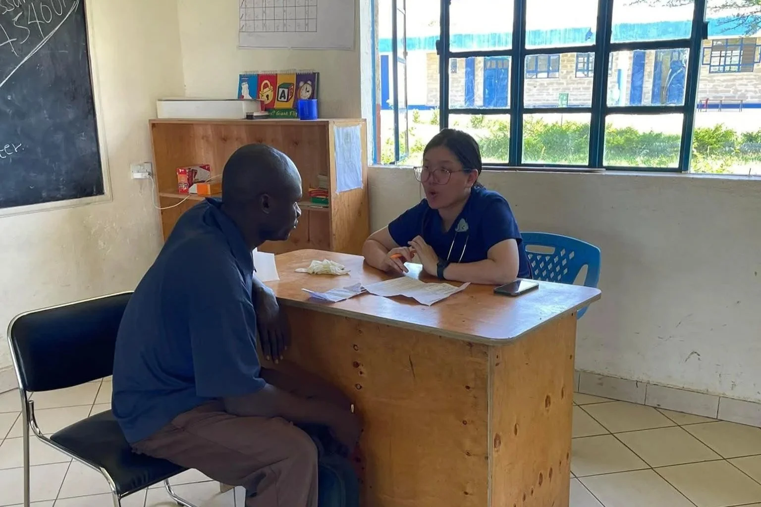 Man conversing with female medical professional at a desk.
