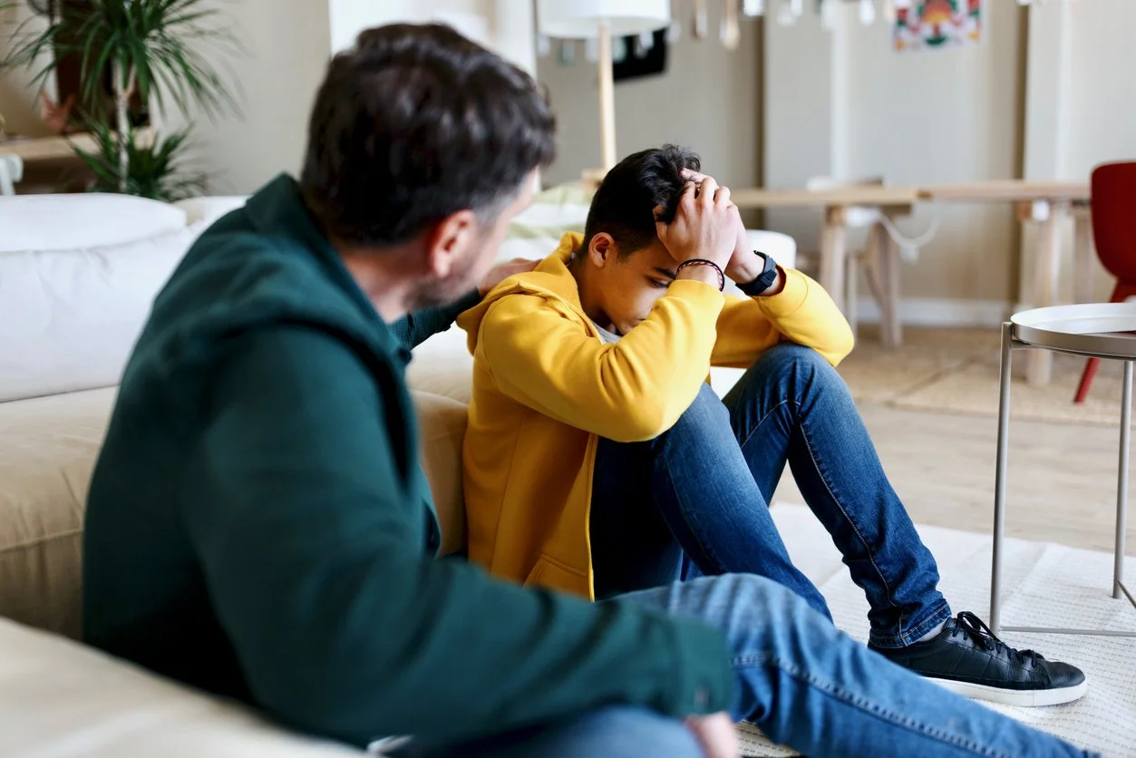 Proper firearm storage importance - A father consoling his teenage son who is showing signs of mental health issues.